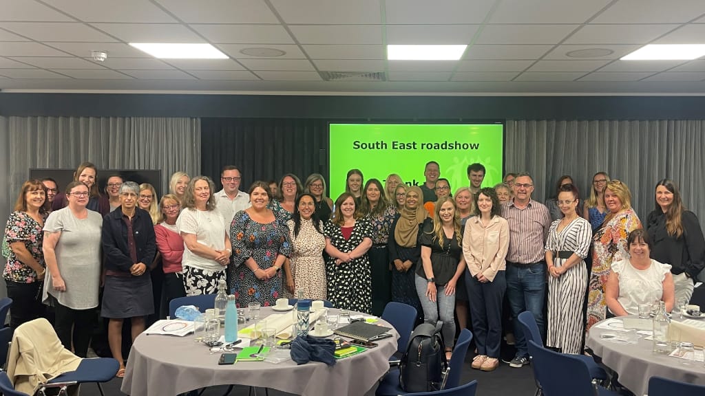 a group of about 40 people pose in front of a slide reading 'South East Roadshow. Thank you